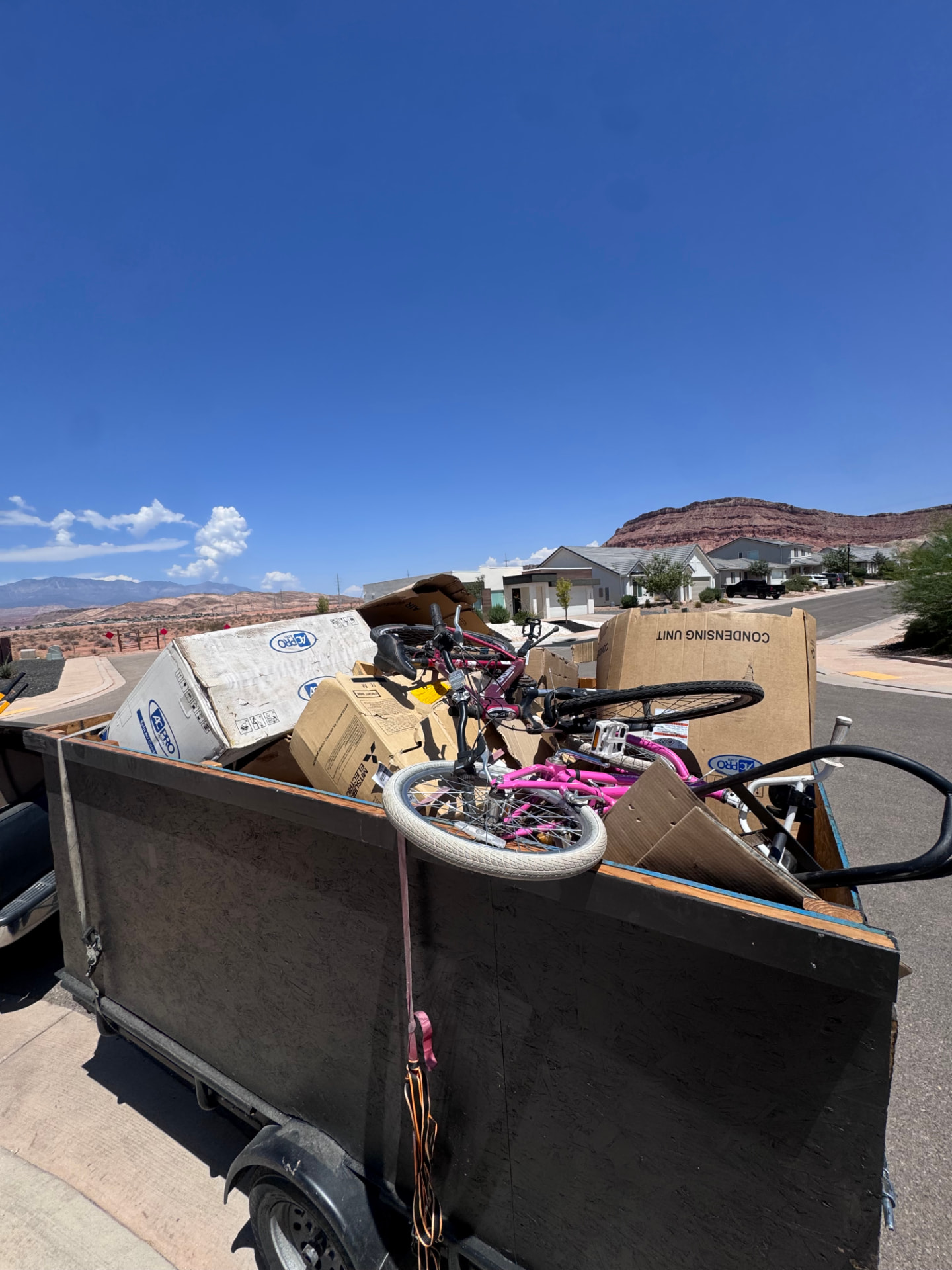 Dump-N-Done trailer loaded with bikes, boxes, and household junk in a St. George, Utah neighborhood